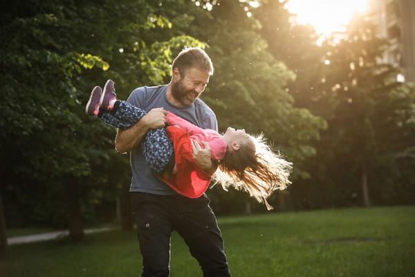 60686786 - devoted father spinning his daughter in circles, bonding, playing, having fun in nature on a bright, sunny day. parenthood, lifestyle, parenting, childhood and family life concept.