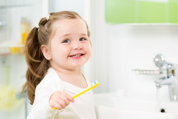 21965611 - smiling child girl brushing teeth in bathroom